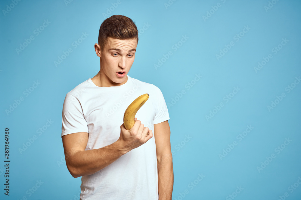 Happy man with fresh fruits gesturing with hands blue background white t-shirt vitamins bananas Happy man with fresh fruits gesturing with hands blue background white t-shirt vitamins bananas
