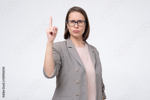 Mature woman raising her finger up warningly. photo