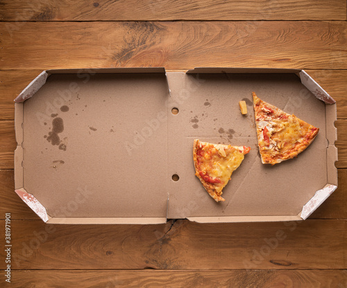 Ugly pizza pieces in opened pizza box on wood