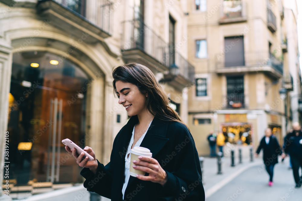 Happy Caucasian hipster girl 20s enjoying mobile messaging during app networking in city, carefree female blogger with takeaway coffee to go reading content publication on website and smiling Happy Caucasian hipster girl 20s enjoying mobile messaging during app networking in city, carefree female blogger with takeaway coffee to go reading content publication on website and smiling