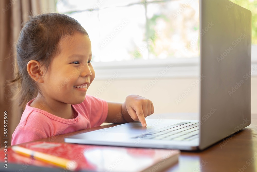 A happy student child learning virtual school at her computer. Online class. A happy student child learning virtual school at her computer. Online class.