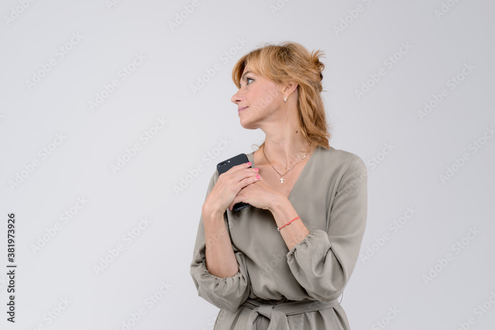 Woman using a mobile phone isolated on a white background looking to the side, empty space Woman using a mobile phone isolated on a white background looking to the side, empty space
