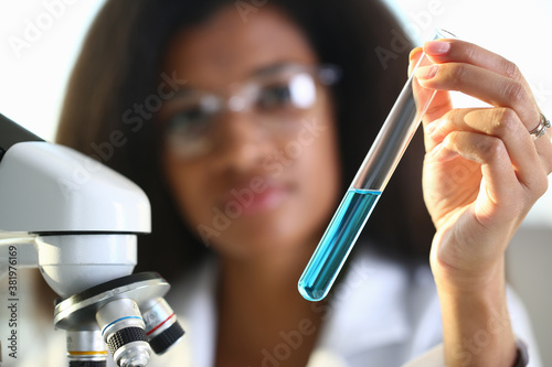 A female chemist holds test tube of glass in his hand overflows liquid solution potassium permanganate conducts an analysis reaction takes various versions reagents using chemical manufacturing.