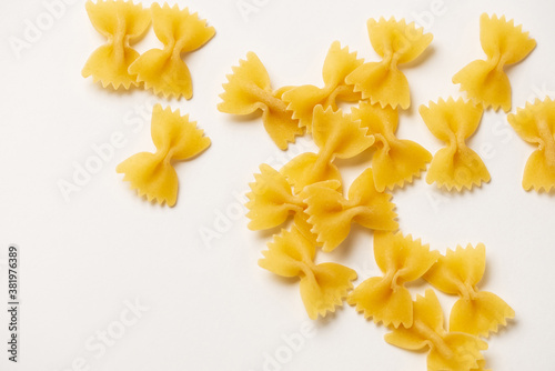 Farfalle - one of types of traditional Italian pasta. Macaroni products are randomly scattered on a white background, for advertising, blogging, cooking recipes, packaging