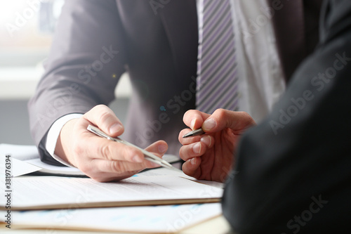 Male arm in suit and tie fill form clipped pad with silver pen closeup. Sign gesture read pact sale agent bank job make note loan credit mortgage investment finance executive chief legal teamwork law photo