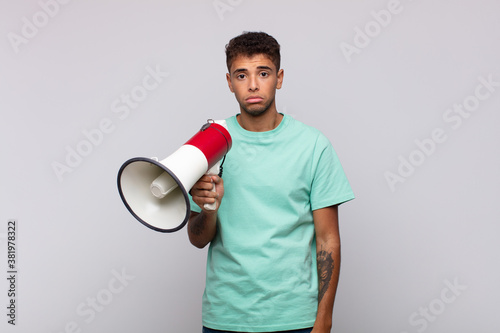 young man with a megaphone feeling sad and whiney with an unhappy look, crying with a negative and frustrated attitude photo