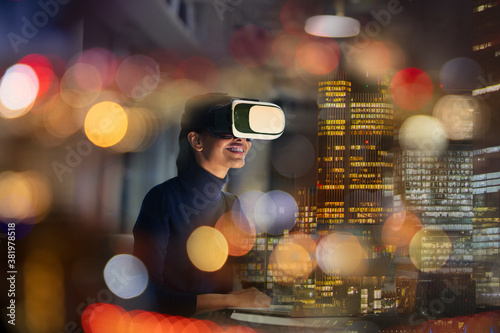 Businesswoman with virtual reality glasses in highrise office at night photo