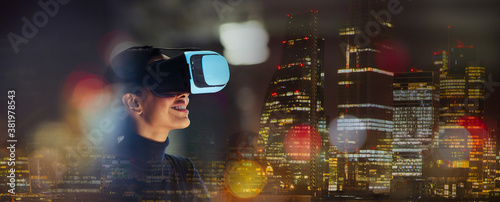 Smiling businesswoman using virtual reality glasses in city at night photo