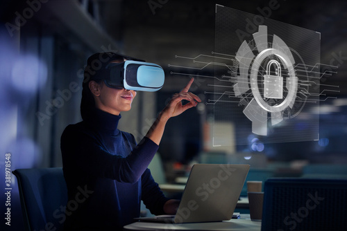 Businesswoman using virtual reality glasses at laptop photo