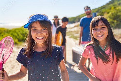 Portrait happy sisters on sunny beach with family