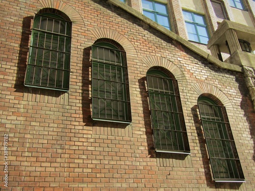 Photography Cascaded slatted windows on orange color brick wall of an old building in Budape