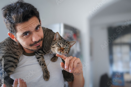gato atigrado gris se acuesta en el cuello de un hombre joven. Primer plano