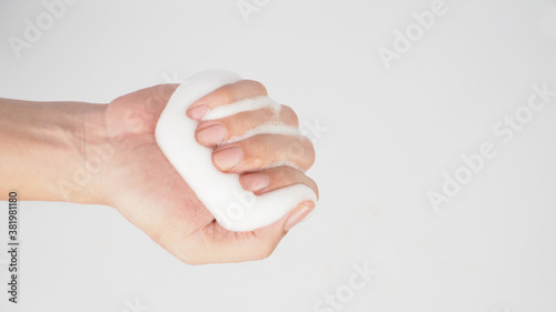 Hand is hold foaming hand soap for washing on white background.