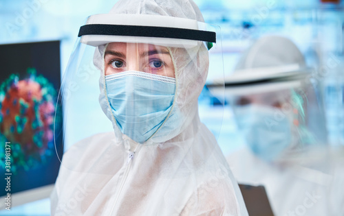 Portrait confident female scientist in clean suit studying coronavirus photo