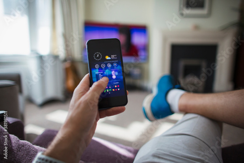 POV Man adjust temperature control on smart phone in living room photo