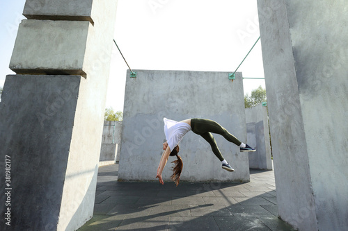 Fotografía A girl does a somersault against a concrete wall