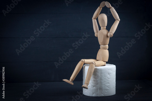 wooden mannequin and toilet paper on a black background