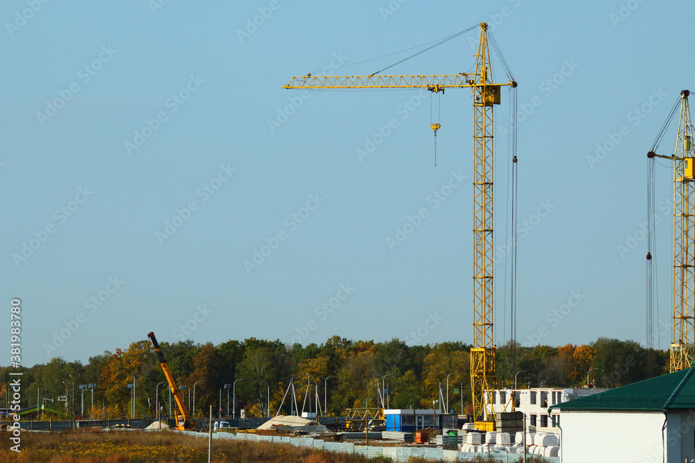 New complex of apartment buildings under construction with cranes in the fields