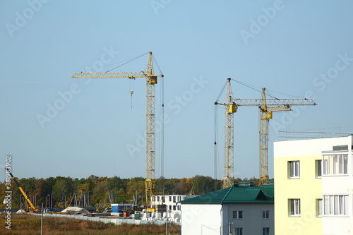 New complex of apartment buildings under construction with cranes in the fields of a countryside