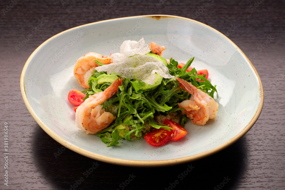Salad with shrimps, tomatoes and arugula, on a white plate, on a dark background Salad with shrimps, tomatoes and arugula, on a white plate, on a dark background