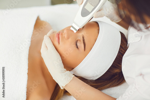 Woman receiving ultrasound apparatus facial cleaning in beauty salon