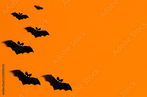 Fotografiet orange background with a flock of black paper bats for Halloween, black paper ba
