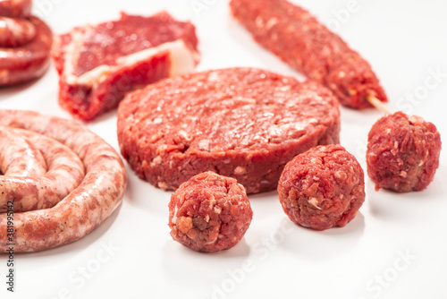 Close-up on raw meatballs, patty, sausage and kebab on white bac