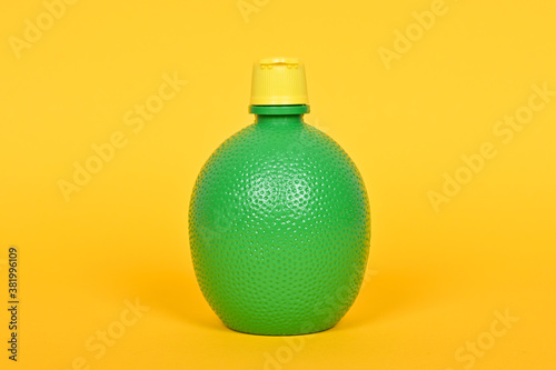 Concentrate lemon juice in a green bottle on a yellow background.