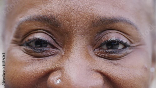 Close up shot of black womans eyes as she looks to camera and smiles