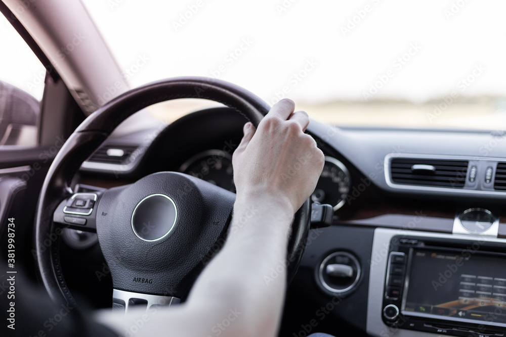 A man drives a car, a hand on the steering wheel, a view from the interior.