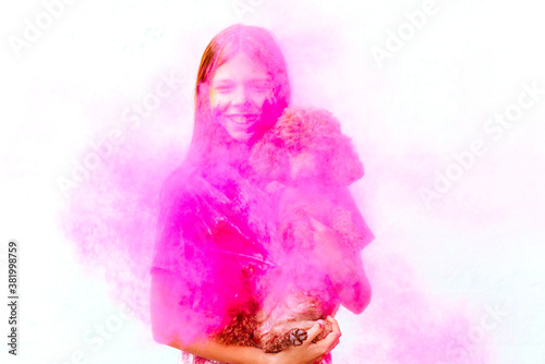 happy girl with dog painted with Holi festival colours on white wall background