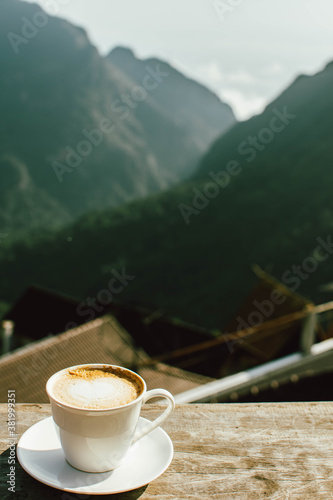 Hot latte coffee in winter morning at hillside with mountain background. Copy space for text. 