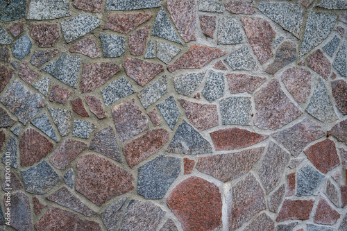 Background wall of red and gray granite pieces of stones fastened with cement, horizontal orientation