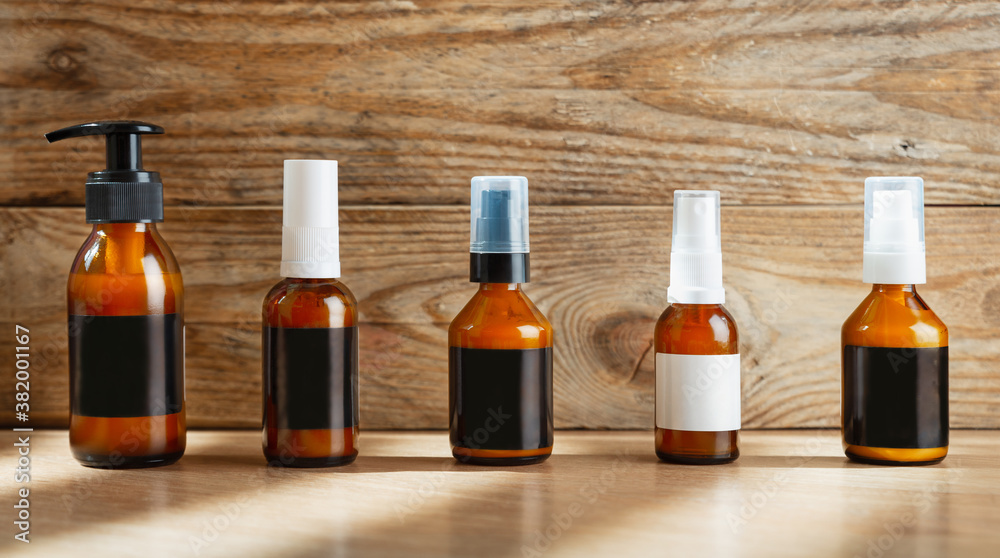 Dark cosmetic amber glass bottles set with blank labels for cosmetics on a wooden background. Dark cosmetic amber glass bottles set with blank labels for cosmetics on a wooden background.