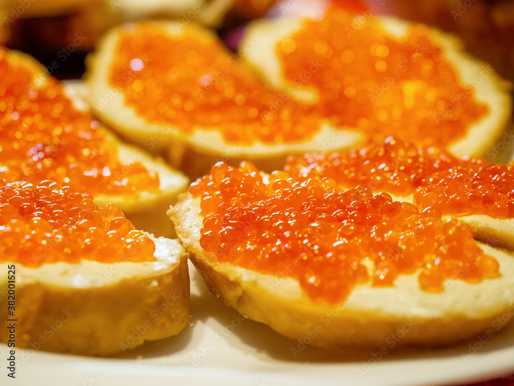 Photo with focus in the center of delicious sandwiches with shiny red caviar