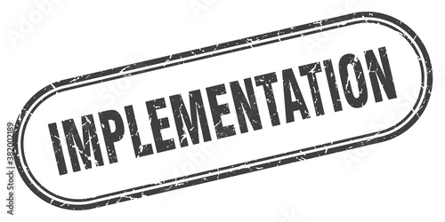 implementation stamp. rounded grunge textured sign. Label
