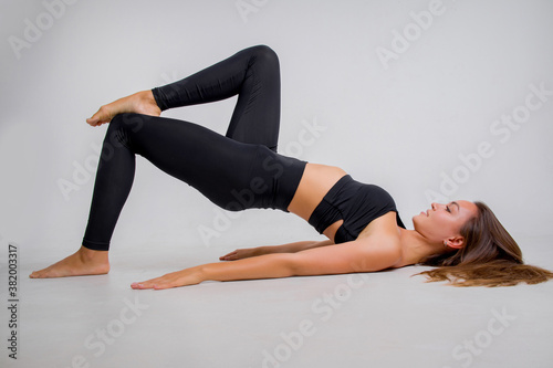 The brunette of an athletic physique goes in for sports in the studio on a white background.