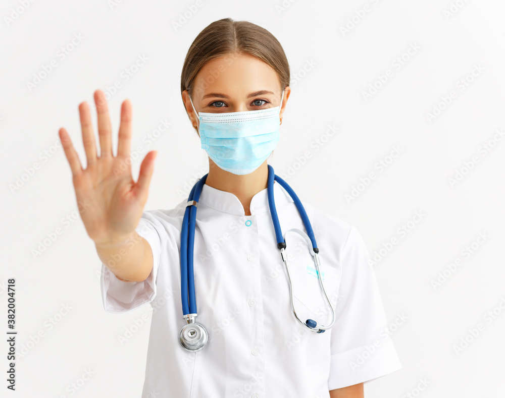 concept of fighting coronavirus infection. a doctor in a protective medical mask shows stop symbol with hand.