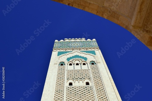 The minaret tower of the Hssana II mosque in Casablanca against a blue sky. photo