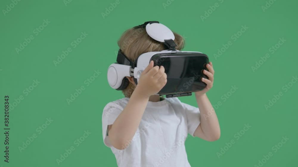 portrait of little child with virtual reality glasses looking around amazed, green backround portrait of little child with virtual reality glasses looking around amazed, green backround