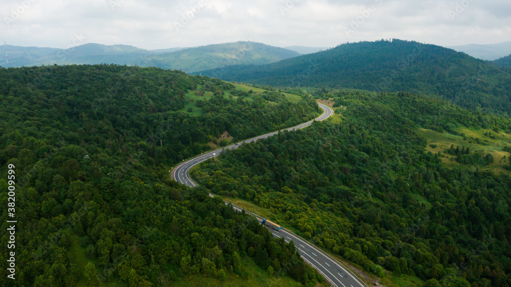 Aerial view over mountain road going through forest landscape