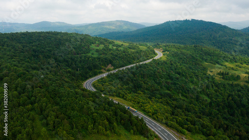 Aerial view over mountain road going through forest landscape