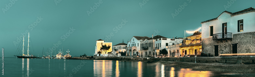 Panoramic view of the coastline, the town hall and old buildings located on Anargirou street at evening, Spetses, Greece.