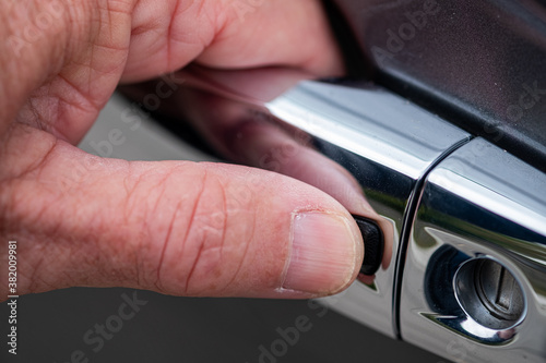 Extreme close up of a man pushing the button on his car door to unlock the car
