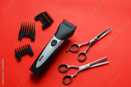 Barber clipper,scissors for haircuts,nozzles for haircuts on a red background.Free space for text.Barber tool.New year at the hairdresser.Discounts and promotions for the new year.New Years hairstyles