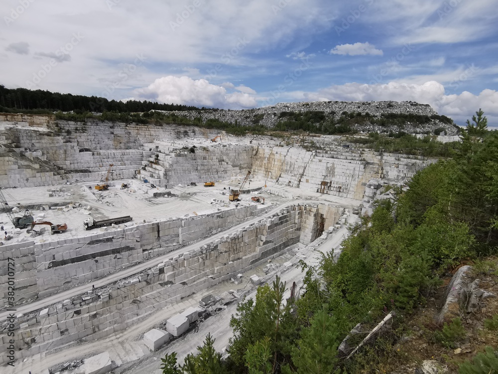 Marble open pit near the Ekaterinburg. Broken stone in Ural mountains. Industry landscape with white stone and sky