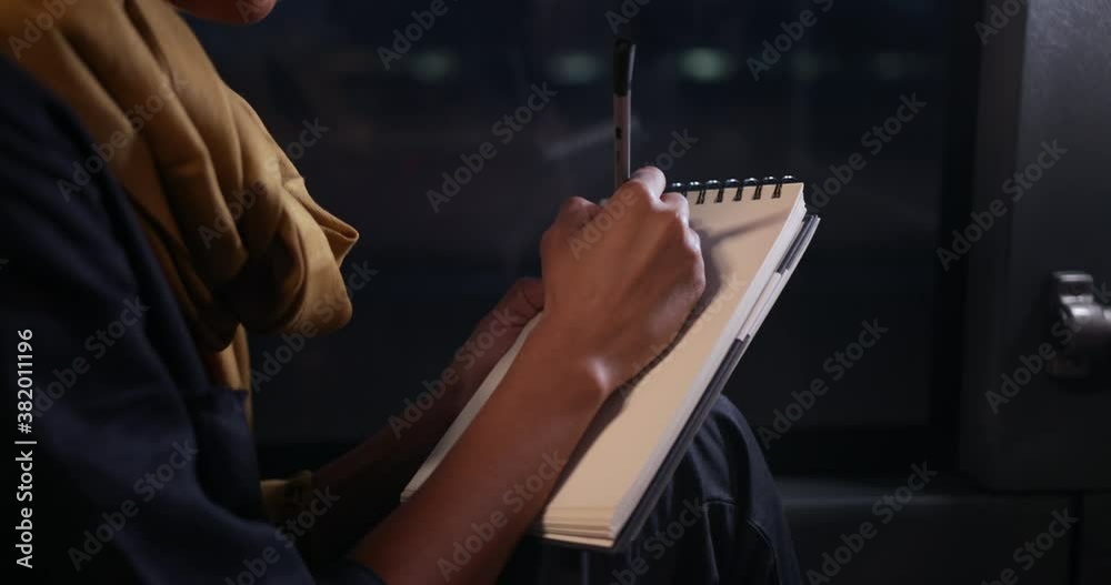 Close-up african-american woman writing with pen on notebook on bus