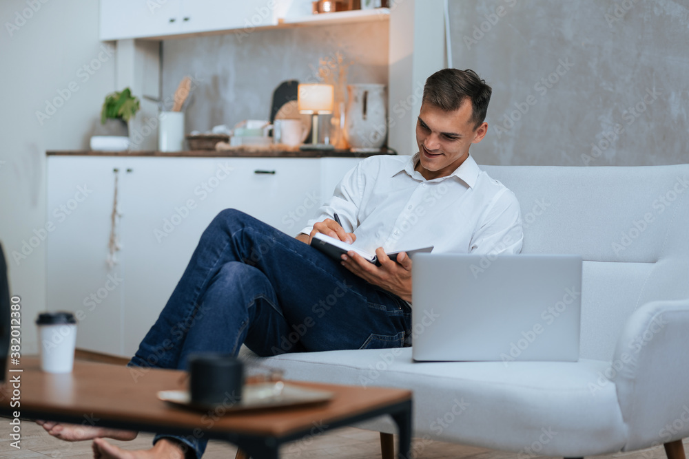 young man taking notes sitting on the couch . young man taking notes sitting on the couch .