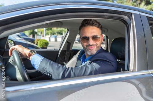 Confident handsome businessman smiling in the car