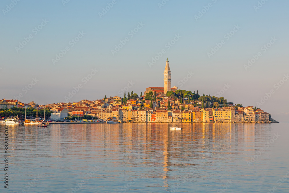 Silhouette of the historic city Rovinj at morning time with light reflections in the water